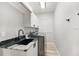 This is a laundry room featuring white cabinets with black hardware, a black sink, and a front load washing machine at 2912 51St E St, Bradenton, FL 34208
