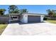Side view of the home showing a carport, garage, and concrete driveway, with a tidy green lawn at 3338 Roslyn Rd, Venice, FL 34293