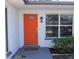 Close-up of the home's front door, showcasing a bright orange color and a window to let in natural light at 3338 Roslyn Rd, Venice, FL 34293