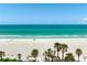 Oceanfront beach with palm trees, beachgoers, and calm blue ocean at 3802 Gulf Of Mexico Dr # A205, Longboat Key, FL 34228