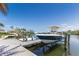 Boat on a lift at a wooden dock on a sunny day with blue skies, with palm trees at 4 Winslow Pl, Longboat Key, FL 34228