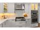 Modern kitchen featuring stainless gas range, oven, microwave, custom hood, and mosaic tile backsplash at 4 Winslow Pl, Longboat Key, FL 34228