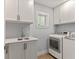 Convenient laundry room with white cabinets, sink, and modern washer and dryer at 4 Winslow Pl, Longboat Key, FL 34228