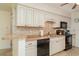 Well-lit kitchen features white cabinets, tiled backsplash, black appliances, and a peninsula counter at 4165 66Th Street W Cir # H, Bradenton, FL 34209