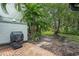 Landscaped backyard with brick patio, grill, mature trees, and lush greenery at 4637 Willow Wood Cir # 44, Sarasota, FL 34241
