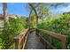 Wooden walkway with brown railings surrounded by lush greenery and trees on a sunny day at 4637 Willow Wood Cir # 44, Sarasota, FL 34241