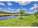 A beautiful backyard with pond, lush green grass, and view of neighboring houses and their manicured lawns at 4925 Coastal Days Ln, Bradenton, FL 34211