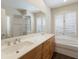 Bathroom featuring double sinks, white cabinets, soaking tub, and plantation shutters at 4998 Cedar Oak Way, Sarasota, FL 34233
