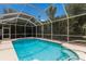 Screened pool enclosure with turquoise pool, sunny skies and lush backyard at 4998 Cedar Oak Way, Sarasota, FL 34233