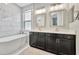 Modern bathroom with a soaking tub, dual sinks, dark cabinets, and marble tile walls and floors at 5515 69Th E Pl, Ellenton, FL 34222