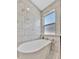 Close up view of a soaking tub with white marble tile, chrome fixtures, and a small window at 5515 69Th E Pl, Ellenton, FL 34222