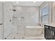 Bright bathroom featuring a soaking tub, rain head shower, and dark vanity with white countertop at 5515 69Th E Pl, Ellenton, FL 34222