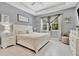 A primary bedroom showcases a tray ceiling, tiled floors, and neutral colored furniture at 5515 69Th E Pl, Ellenton, FL 34222
