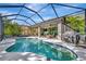 Relaxing screened pool with outdoor living area features hot tub, outdoor dining, and grill, surrounded by tropical trees at 5515 69Th E Pl, Ellenton, FL 34222