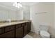 Bathroom with a tiled floor, dark cabinets, granite counters, toilet and lighting at 5604 Palmer Cir # 103, Bradenton, FL 34211