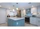 A bright kitchen features white cabinets, stainless steel appliances, and a blue island with a granite countertop at 5750 Midnight Pass Rd # 203, Sarasota, FL 34242