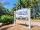 A community sign at Casarina, showing the community name and address, surrounded by greenery and trees at 5880 Midnight Pass Rd # 202, Sarasota, FL 34242