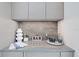 Chic bar area with custom cabinetry, stone backsplash, elegant glassware, and decorative accents for stylish entertaining at 590 De Narvaez Dr, Longboat Key, FL 34228