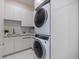 Modern laundry room with sleek white cabinetry and stacked washer and dryer at 590 De Narvaez Dr, Longboat Key, FL 34228