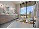 This is the Primary bathroom with double sinks and a modern soaking tub overlooking lush tropical landscape at 590 De Narvaez Dr, Longboat Key, FL 34228