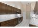 Spacious kitchen featuring dark wood cabinets, granite countertops, and white tiled floors at 6755 Approach Rd # 31, Sarasota, FL 34238