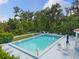 Community pool with surrounding deck, lounge chairs, tables, and lush landscaping at 6755 Approach Rd # 31, Sarasota, FL 34238