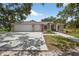 Single-story home featuring a three-car garage, landscaping, and a paved driveway and walkway at 6875 Myakka Valley Trl, Sarasota, FL 34241