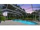 A backyard pool and hot tub under a screened enclosure, surrounded by plants and a green yard at 6875 Myakka Valley Trl, Sarasota, FL 34241