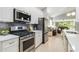 Beautiful kitchen with stainless steel appliances, granite countertops, gray backsplash, and views to the living area and backyard at 7343 Birds Eye Ter, Bradenton, FL 34203