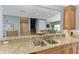 Open-concept kitchen with granite counters, stainless steel sink, wooden cabinets, and barstool seating for casual dining at 7820 34Th W Ave # 102, Bradenton, FL 34209