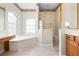 Bright bathroom featuring a large tub under a window, with a glass-enclosed shower and wooden vanity at 8312 Misty Lake Cir, Sarasota, FL 34241
