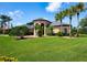 Beautifully landscaped one story home featuring a lush lawn, mature trees, and inviting covered front entry way at 8312 Misty Lake Cir, Sarasota, FL 34241