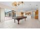 Open game room with tile floors, billiard table, access to an outdoor lanai and views of the kitchen with stainless appliances at 8312 Misty Lake Cir, Sarasota, FL 34241