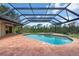 Enclosed pool and jacuzzi, with brick patio overlooking a pond at 8312 Misty Lake Cir, Sarasota, FL 34241