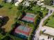 Aerial view of well-maintained tennis courts surrounded by lush greenery and manicured landscapes at 8312 Misty Lake Cir, Sarasota, FL 34241