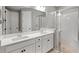 Modern bathroom with double sink vanity, large mirror, and glass-enclosed shower with unique tile flooring at 9040 Tequila Sunrise Dr, Sarasota, FL 34241