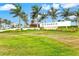 A beautiful Sky Ranch community entrance with a lush green lawn, palm trees and bright blue skies at 9040 Tequila Sunrise Dr, Sarasota, FL 34241