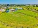 An aerial view of a large neighborhood dog park complete with shaded seating, lush lawn and fencing at 9040 Tequila Sunrise Dr, Sarasota, FL 34241