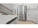 Stylish kitchen showcases stainless steel refrigerator and white cabinets with access to the staircase at 9040 Tequila Sunrise Dr, Sarasota, FL 34241