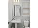Cozy powder room with pedestal sink, rounded mirror, modern faucet, toilet and window with blinds at 9040 Tequila Sunrise Dr, Sarasota, FL 34241