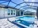 Luxurious screened-in pool area with a spa, outdoor kitchen, and modern design features at 1167 Boundary Blvd, Rotonda West, FL 33947