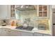 Close-up on gas stove with stainless steel vent hood and marble backsplash and countertop at 13220 Swiftwater Way, Lakewood Ranch, FL 34211