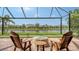 Screened-in patio with wooden chairs, a fire pit, and a beautiful view of the lake and surrounding community at 13220 Swiftwater Way, Lakewood Ranch, FL 34211