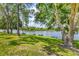 A tranquil lakefront backyard with mature trees offers a serene setting for enjoying nature and outdoor activities at 13503 22Nd E Ct, Parrish, FL 34219