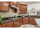 Gourmet kitchen features gas range, dark cabinetry, stainless hood, granite counters, tile backsplash, and bar seating at 13503 22Nd E Ct, Parrish, FL 34219