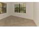 Bright bedroom with neutral tile flooring, two windows, and a view of lush outdoor greenery at 1375 Backspin Dr, Englewood, FL 34223