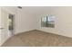 Empty bedroom with neutral carpet, white walls, a window with blinds, and an open doorway to the hall at 1375 Backspin Dr, Englewood, FL 34223