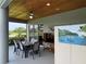 Screened-in lanai with wood ceiling, dining table, television, and island-themed art at 14714 5Th Ne Ter, Bradenton, FL 34212