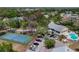 Scenic aerial view of community amenities including tennis court, pool, parking, and common building nestled among lush trees at 1500 Sunset Rd # B4, Tarpon Springs, FL 34689