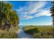 Picturesque beach path leading to the ocean with palm trees and lush vegetation at 1500 Sunset Rd # B4, Tarpon Springs, FL 34689